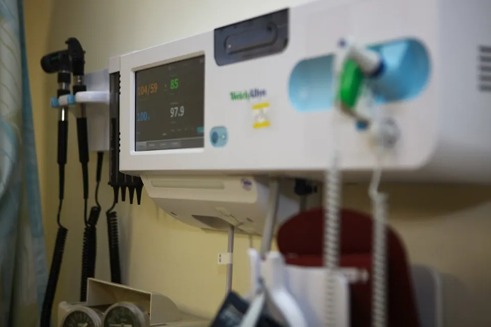 A wall-mounted blood pressure monitor in a clinic exam room