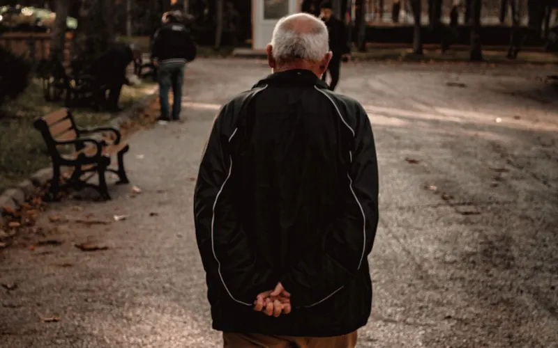 A man in his sixties walking on a park path