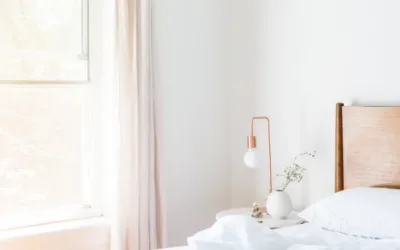 A bedroom with daylight coming through a large window beside the bed in the morning