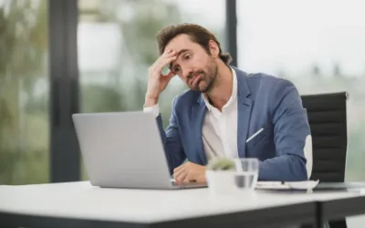 A man sitting at a desk with his head resting on his hand
