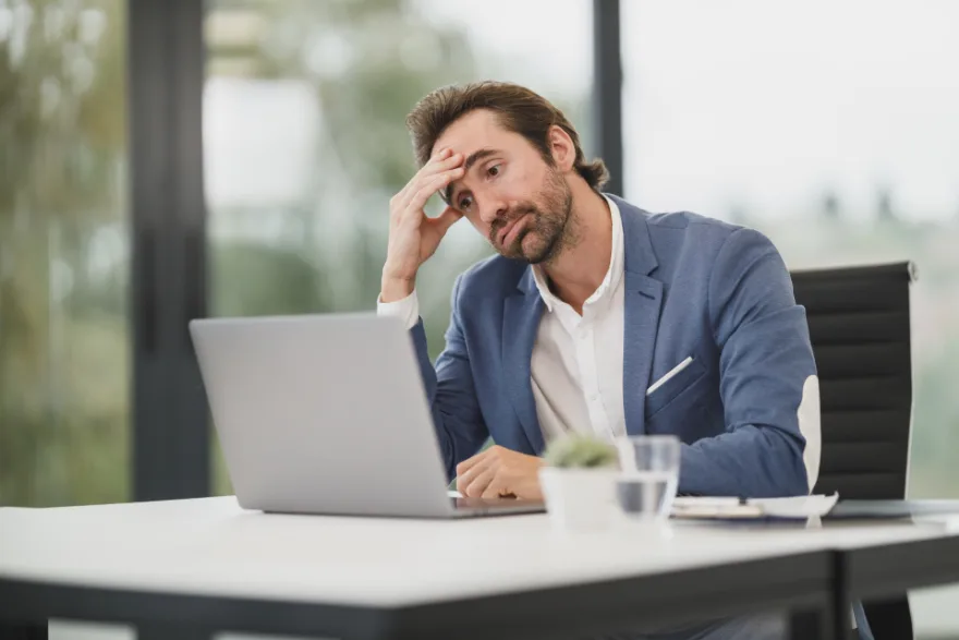 A man sitting at a desk with his head resting on his hand